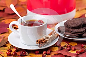 Tea with chocolate cookies on a background of autumn leaves