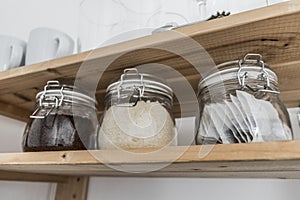 Tea, coffee and sugar in preserving jars on wooden shelf