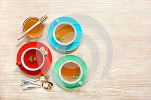 Tea Collection of three different types of tea - mint, hibiscus and herbal tea in cups on wood background.