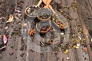 Tea concept. Different kinds of tea in wooden spoons on weathered wood background selective focus.