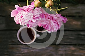 Tea in country style in summer garden in the village. Two cups of black tea on wooden boards and blooming peony flowers in