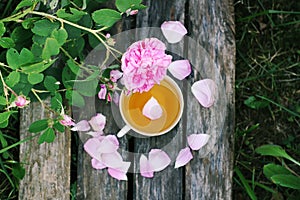 Tea in country style in summer garden in the village. Vintafe cup of green herbal tea on weathered wooden boards and blooming pink