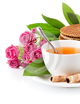 Tea in cup with biscuits and bouquet roses