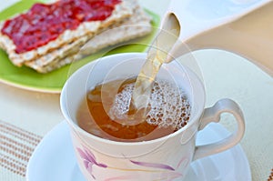 Tea in cup with crispy bread and jam