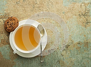 Tea cup with fresh tea leaves and cookie