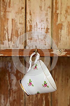 Tea cup hanging on a hook in old wooden cupboard