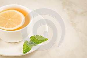 tea cup with a lemon and mint/tea cup with a lemon and mint on a white marble background. Selective focus and copy space