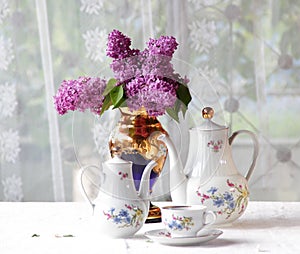 Tea in a cup, and a lilac bouquet on a table