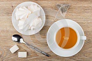 Tea in cup, meringue in saucer, sugar and teaspoon