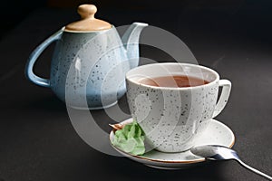 Tea cup with tea pot over black background. Tea time