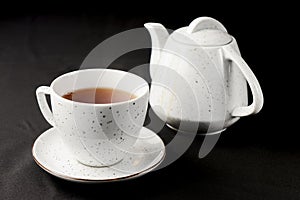 Tea cup with tea pot over black background. Tea time