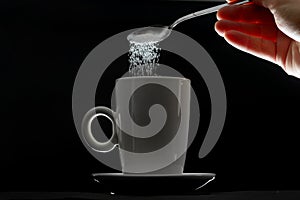 Tea cup and pouring sugar spoon