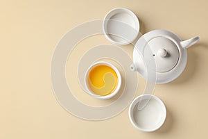 Tea cup set with teapot on beige background, top view