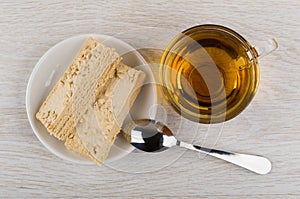 Tea in cup, wafer cake with peanuts in saucer, teaspoon