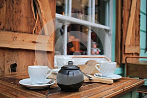 Tea cups and teapot on a table at an outside cafe.