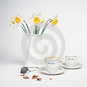 Tea with daffodils in a white vase