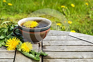 Tea from dandelion in a rustic earthenware cup on a wooden tabl