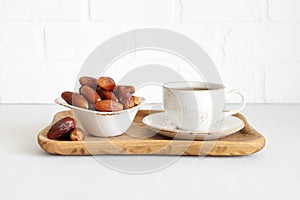 Tea and dates in a wooden tray. Dried dates on white background. Natural sweets. Food for Ramadan