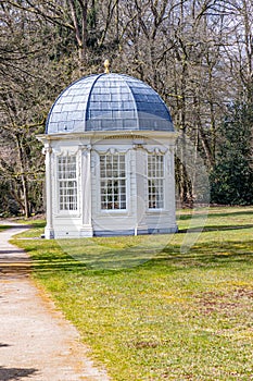 Tea dome or theekoepel or Gloriette next a dirt trail, green grass and bare trees in the background
