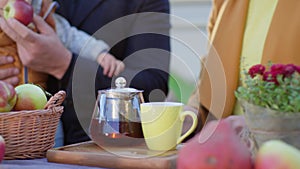 Tea for family outdoors, woman`s hand pour drink into cup and give it to little son, kid boy does not want to drink and