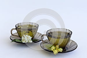 Tea and flowers. two dark glass cups with herbal hot linden tea and jasmine tea