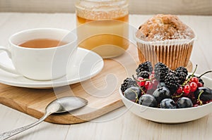 tea with fresh berries, cake and honey/healthy breakfast: tea with fresh berries, cake and honey on a wooden surface. Selective