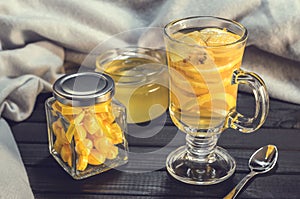 Tea with ginger and lemon in a glass cup and yellow sweets