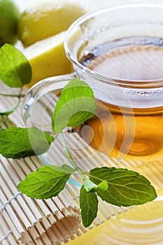 Tea in the glass cup with lemon and fresh mint leaves - herbal h