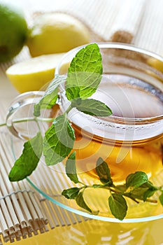 Tea in the glass cup with lemon and fresh mint leaves - herbal h