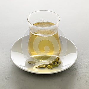 Tea glass with fresh made hot Cardamon tea and seed pods