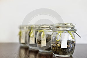 Tea in glass jars on wooden table with white background