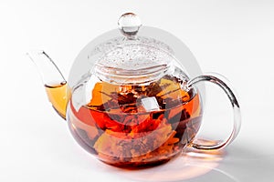 Tea in a glass teapot with a blooming large flower. Teapot with exotic green tea on white background