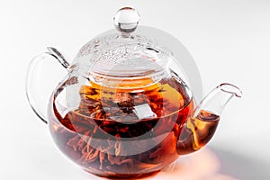 Tea in a glass teapot with a blooming large flower. Teapot with exotic green tea on white background