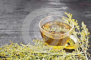 Tea of gray wormwood in glass cup on board