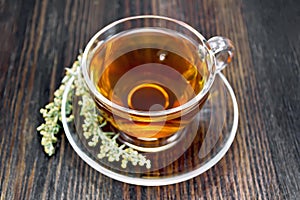 Tea with gray wormwood in glass cup on dark board