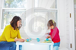 Tea just like how Mom makes it. an adorable little girl having a tea party with her mother at home.