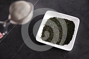 tea leaves and tea strainer on black background