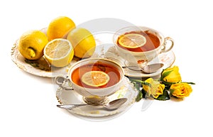 Tea with lemon in an antique porcelain cup and saucer, yellow roses