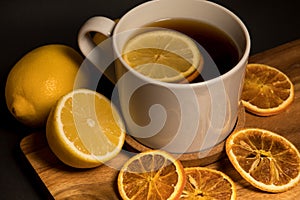 Tea with lemon and dried tangerine on wooden board.