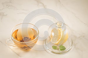 Tea with a lemon and mint in glass cup/tea with a lemon and mint in glass cup on a white marble background