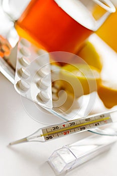 Tea with lemons and flu pills with thermometer - grippe remedy photo