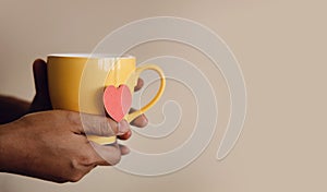 Tea Lover Concept. Hand Holding a Cup of Tea. Eco-Friendly Style Tag made as Heart Shape and Hanging on Cup. Green, Oolong,