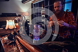 Tea master in kimono making natural tea in the dark room with a wooden interior, watching on tea leaves during brewing