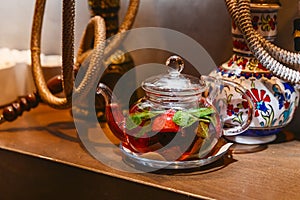 Tea with mint and strawberries in a transparent teapot