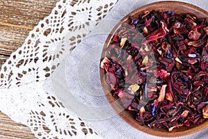 Tea mix of karkade, flowers and berries in a saucer and on the textile