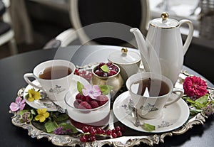 Tea in old porcelain cups, panakota dessert and raspberry on an old silver tray. Retro.