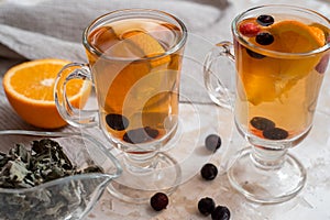 Tea with orange. Dark wooden background. An old book and gingerbreads in the background