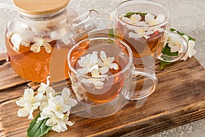 tea party time. two glass modern cups and a teapot with jasmine aromatic tea on the original wooden board.