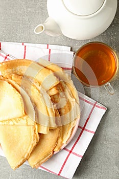Tea, and plate of thin pancakes on gray table