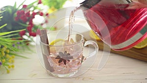 Tea is poured into a glass transparent cup on a wooden table